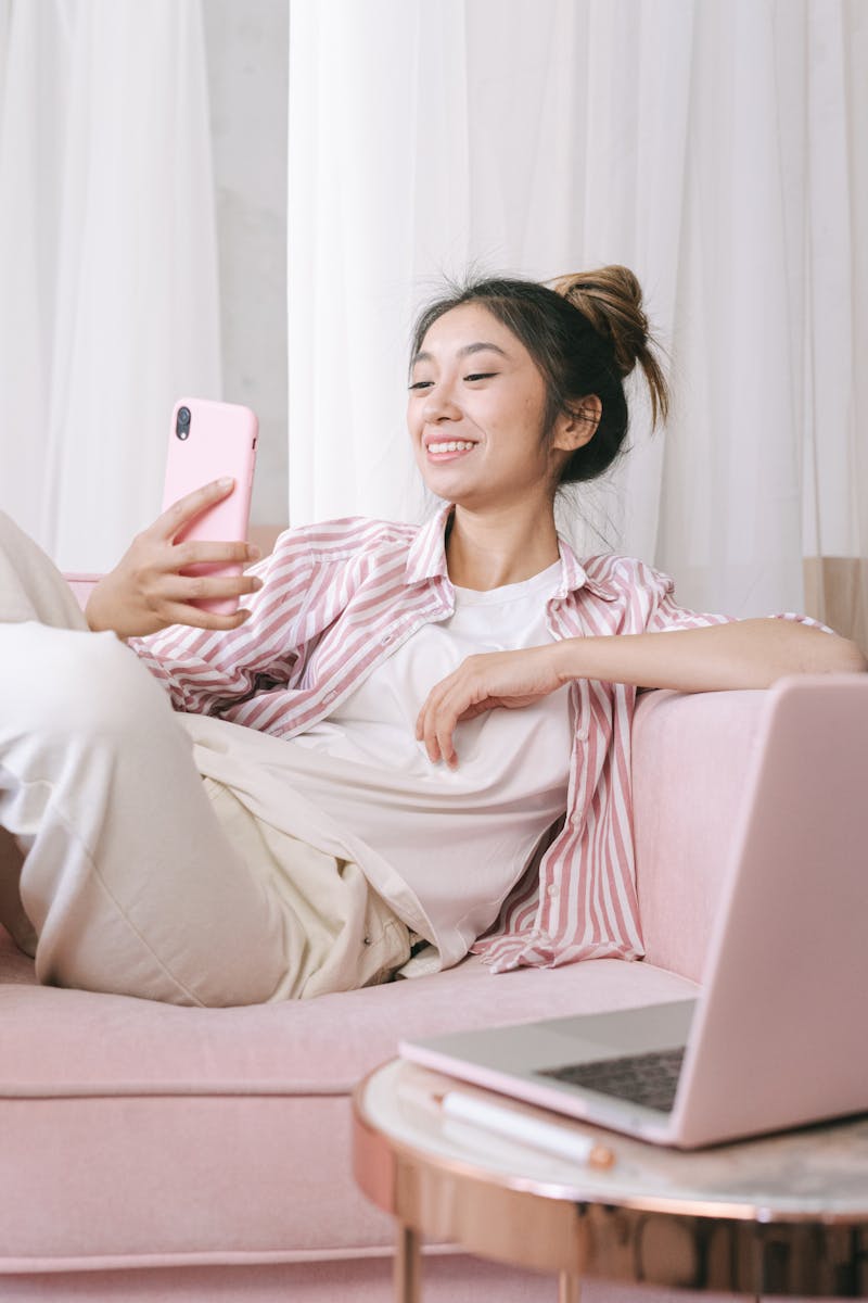 A Woman Sitting on the Couch Smiling while Holding Her Phone